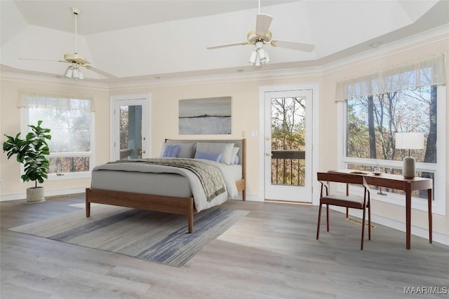 bedroom featuring ceiling fan, a raised ceiling, crown molding, wood-type flooring, and access to outside