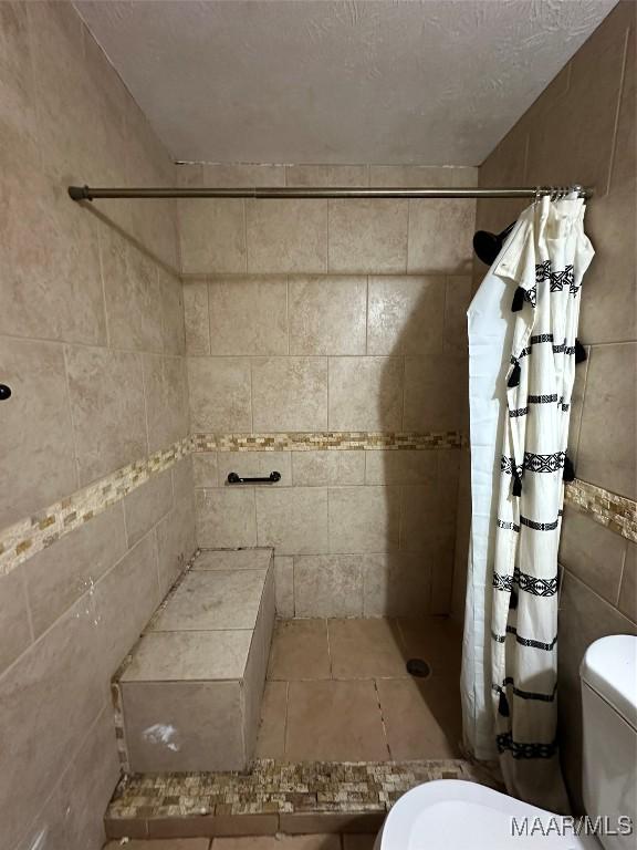 bathroom with toilet, a textured ceiling, and walk in shower