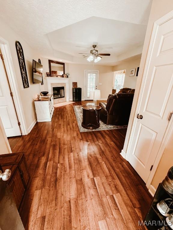 living room featuring a textured ceiling, ceiling fan, and dark wood-type flooring