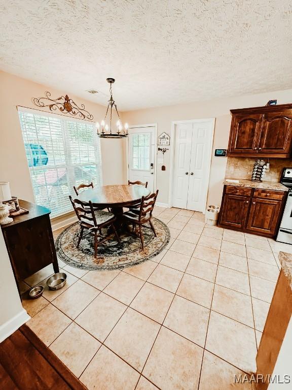 dining area with a notable chandelier, light tile patterned floors, and a textured ceiling