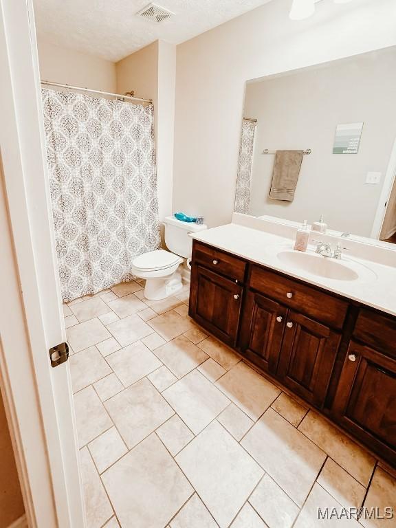 bathroom with vanity, toilet, and a textured ceiling