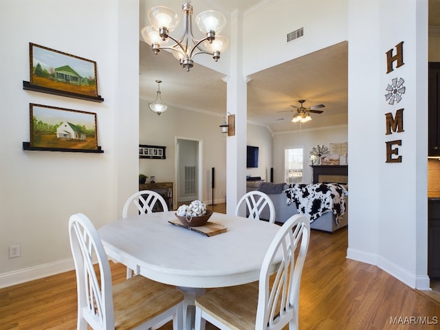 dining room featuring ceiling fan with notable chandelier, dark hardwood / wood-style flooring, and crown molding