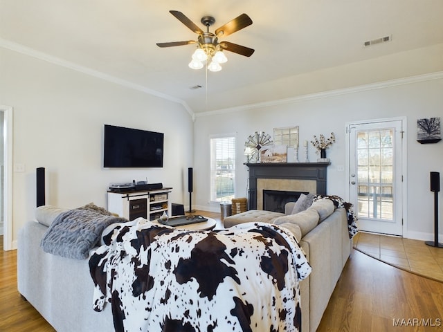 living room featuring hardwood / wood-style flooring, ceiling fan, a healthy amount of sunlight, and crown molding