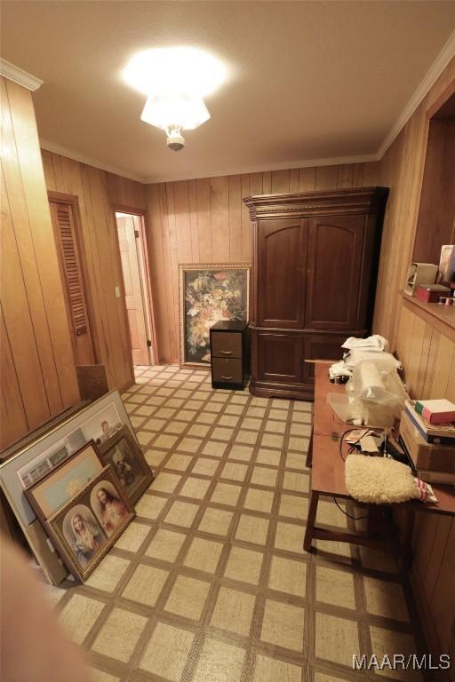 interior space with ornamental molding, light floors, and wooden walls