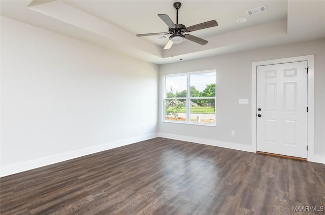 unfurnished room with a tray ceiling, ceiling fan, and dark hardwood / wood-style floors