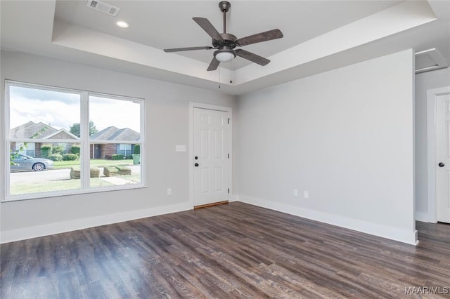 unfurnished room featuring ceiling fan, dark hardwood / wood-style floors, and a raised ceiling