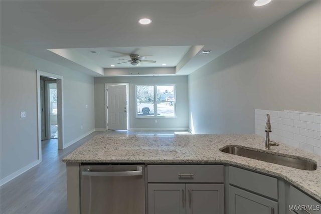 kitchen featuring visible vents, a raised ceiling, light stone counters, a sink, and stainless steel dishwasher