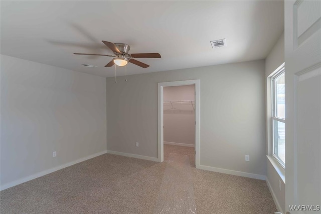 unfurnished bedroom featuring light colored carpet, visible vents, a spacious closet, and baseboards