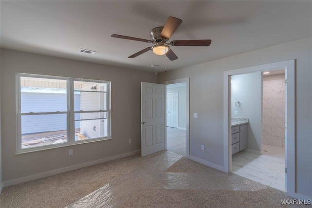 unfurnished bedroom featuring baseboards, visible vents, light colored carpet, ensuite bath, and ceiling fan