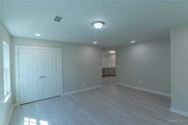 unfurnished room with recessed lighting, wood finished floors, visible vents, and baseboards