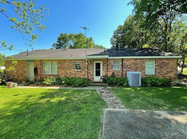 ranch-style home featuring cooling unit and a front lawn