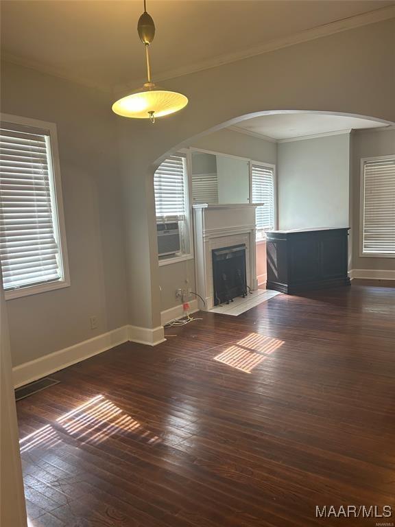 unfurnished living room featuring cooling unit, plenty of natural light, and dark wood-type flooring