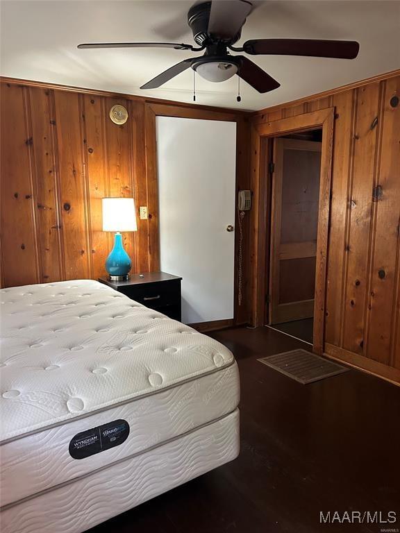 bedroom featuring ceiling fan and wood walls