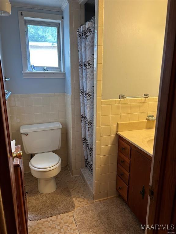 bathroom with a shower with curtain, vanity, tile walls, tile patterned flooring, and toilet