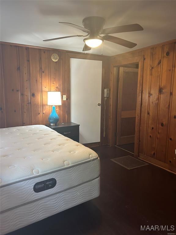 unfurnished bedroom with ceiling fan and wood walls