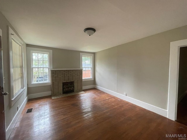 unfurnished living room with wood-type flooring and a brick fireplace