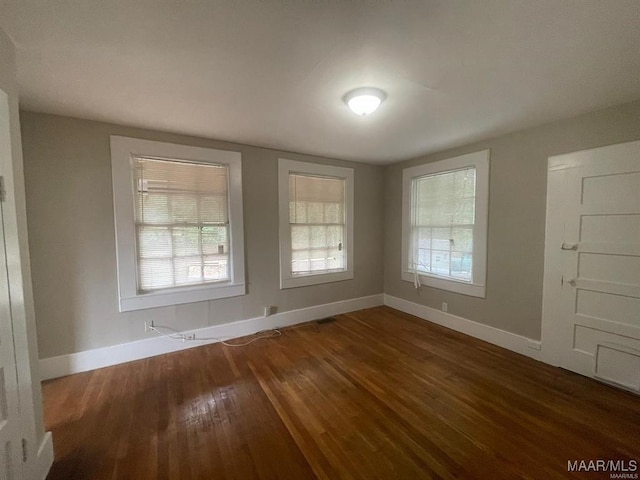 unfurnished room with dark wood-type flooring