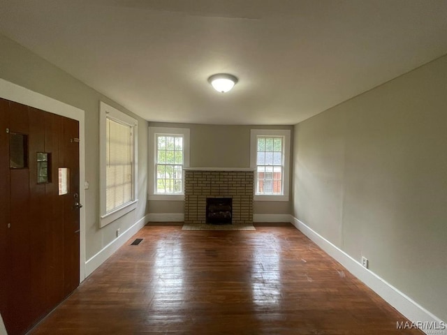 unfurnished living room featuring dark hardwood / wood-style floors and a brick fireplace