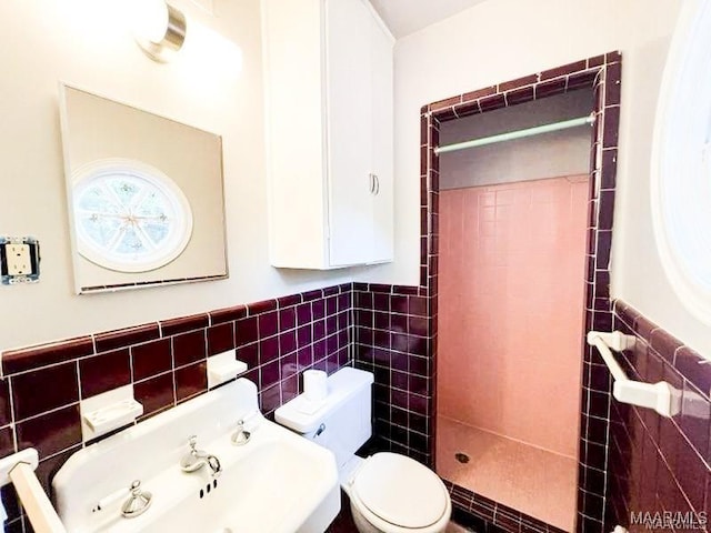 bathroom with a tile shower, tile walls, and toilet