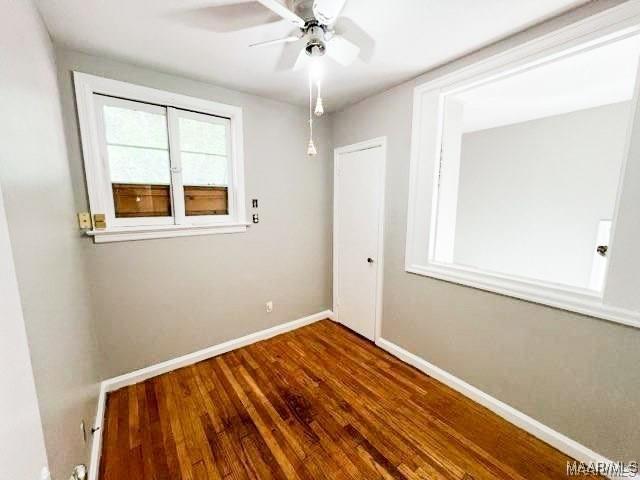 empty room with ceiling fan and dark hardwood / wood-style flooring