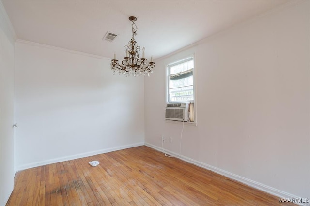 spare room with a notable chandelier, light hardwood / wood-style floors, and crown molding