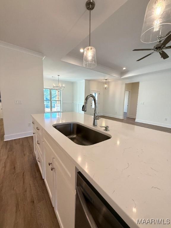 kitchen with dark wood-style floors, a tray ceiling, pendant lighting, stainless steel dishwasher, and a sink