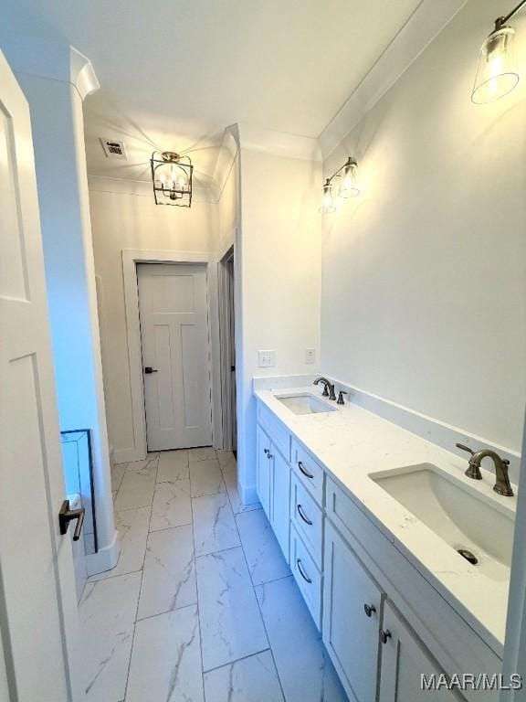 bathroom featuring double vanity, marble finish floor, ornamental molding, and a sink