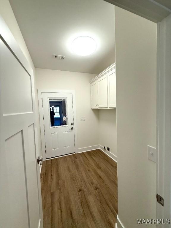 laundry area featuring dark wood-style floors, cabinet space, visible vents, and baseboards