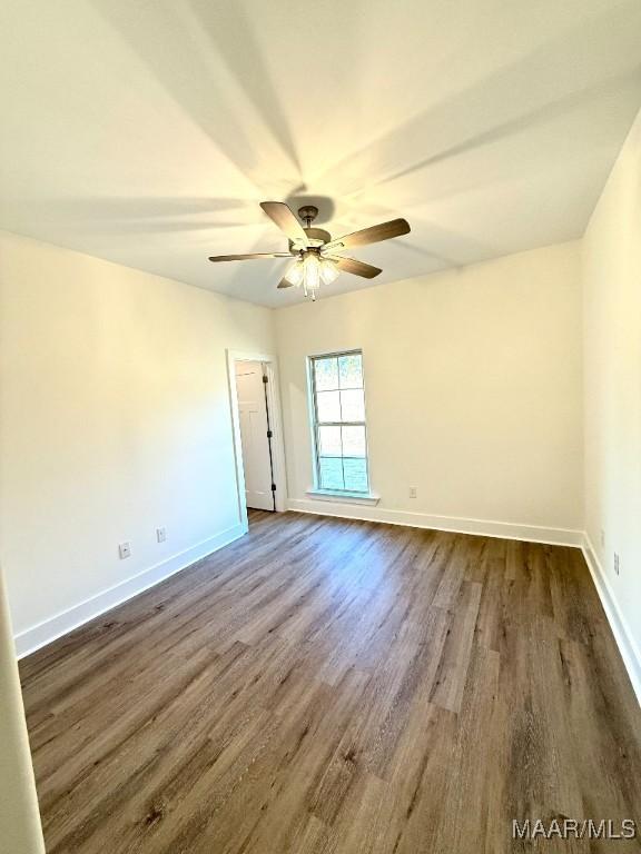 spare room with ceiling fan, baseboards, and dark wood-type flooring