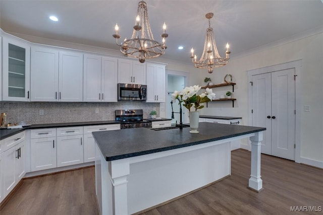 kitchen with decorative backsplash, appliances with stainless steel finishes, a center island, white cabinetry, and hanging light fixtures