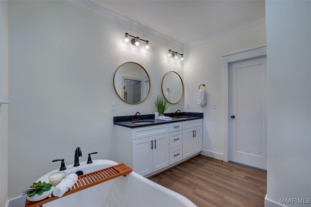 bathroom featuring hardwood / wood-style flooring, vanity, a bathing tub, and crown molding