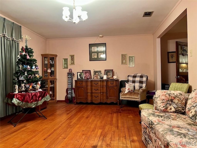 living area featuring a notable chandelier, light hardwood / wood-style floors, and ornamental molding