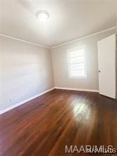 spare room featuring crown molding and dark wood-type flooring