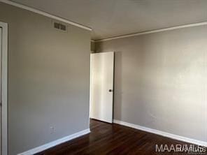 empty room with dark hardwood / wood-style floors and ornamental molding