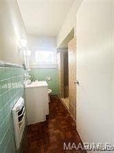 bathroom with parquet floors, tile walls, and toilet