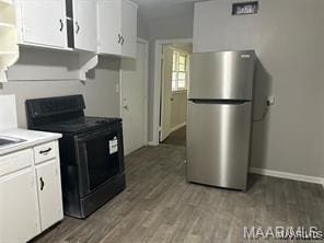 kitchen with light hardwood / wood-style floors, stainless steel fridge, white cabinetry, and black range with electric cooktop