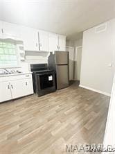 kitchen featuring range, stainless steel refrigerator, white cabinets, and light wood-type flooring