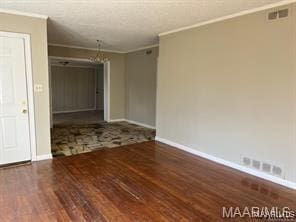 spare room featuring hardwood / wood-style floors, crown molding, and a chandelier