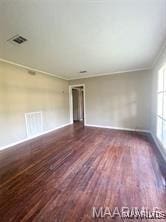 spare room with crown molding and dark wood-type flooring