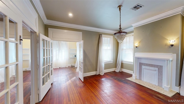 unfurnished dining area featuring french doors, dark hardwood / wood-style flooring, an inviting chandelier, and crown molding