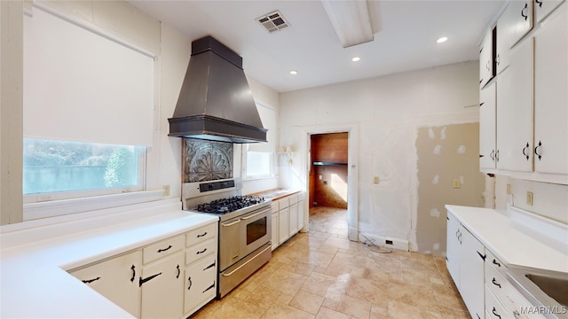 kitchen featuring stainless steel gas range oven, white cabinetry, and custom exhaust hood