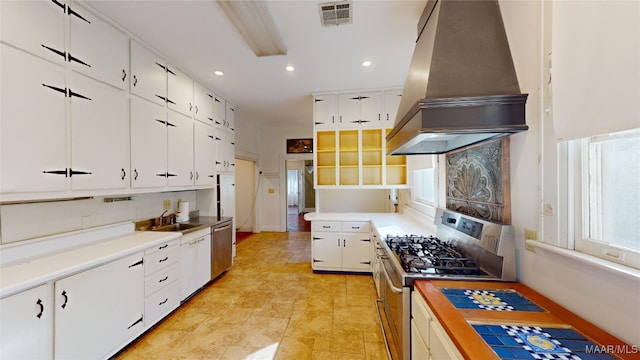 kitchen featuring appliances with stainless steel finishes, wood counters, white cabinetry, sink, and custom range hood