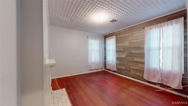 spare room with wood-type flooring and wooden walls