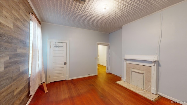 unfurnished living room with crown molding, hardwood / wood-style floors, and wood walls