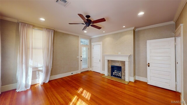 unfurnished living room with hardwood / wood-style floors, ceiling fan, crown molding, and a wealth of natural light