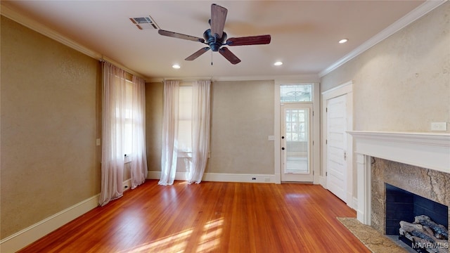 unfurnished living room with a tiled fireplace, hardwood / wood-style floors, crown molding, and ceiling fan