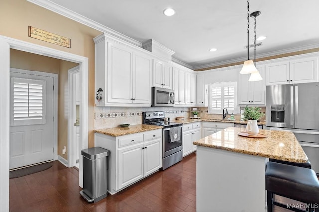 kitchen with a center island, white cabinets, decorative light fixtures, and appliances with stainless steel finishes