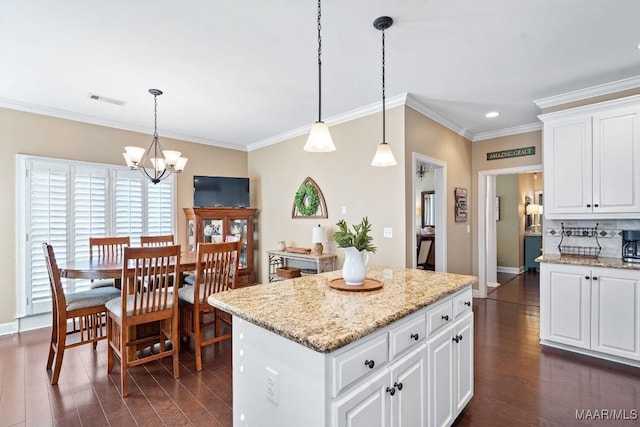 kitchen featuring white cabinetry, crown molding, a center island, and hanging light fixtures