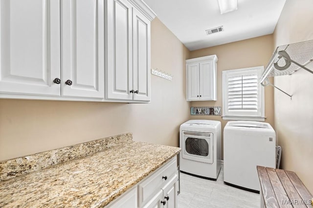 laundry room featuring washer and clothes dryer and cabinets