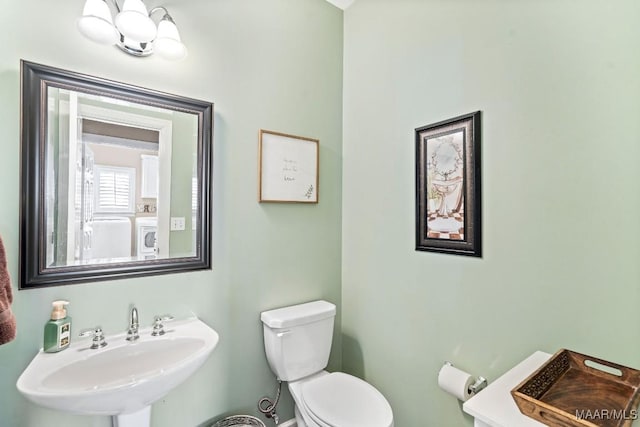 bathroom featuring toilet, sink, and washer / dryer